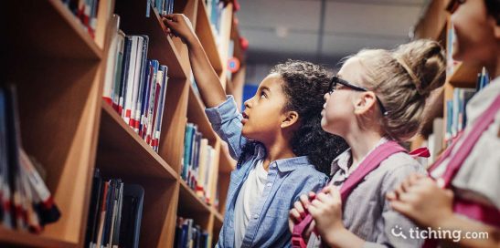 Imagen: niña escogiendo libros en la biblioteca escolar