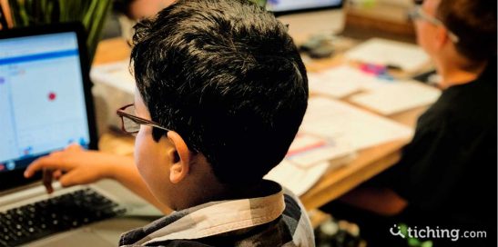 Niños en el aula con ordenadores y papel para ilustrar la autonomía y autorregulación